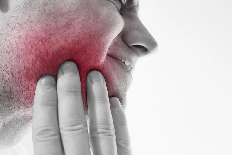 Man pressing his hand against his jaw because of tooth pain